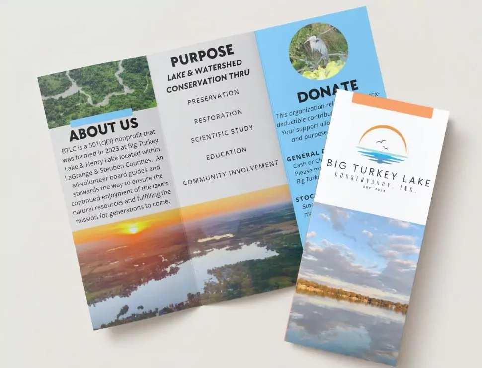 The Conservancy's printed trifold brochure lying on a table, open to the About Us and Purpose panels, next to the folded cover showing the sunrise logo.