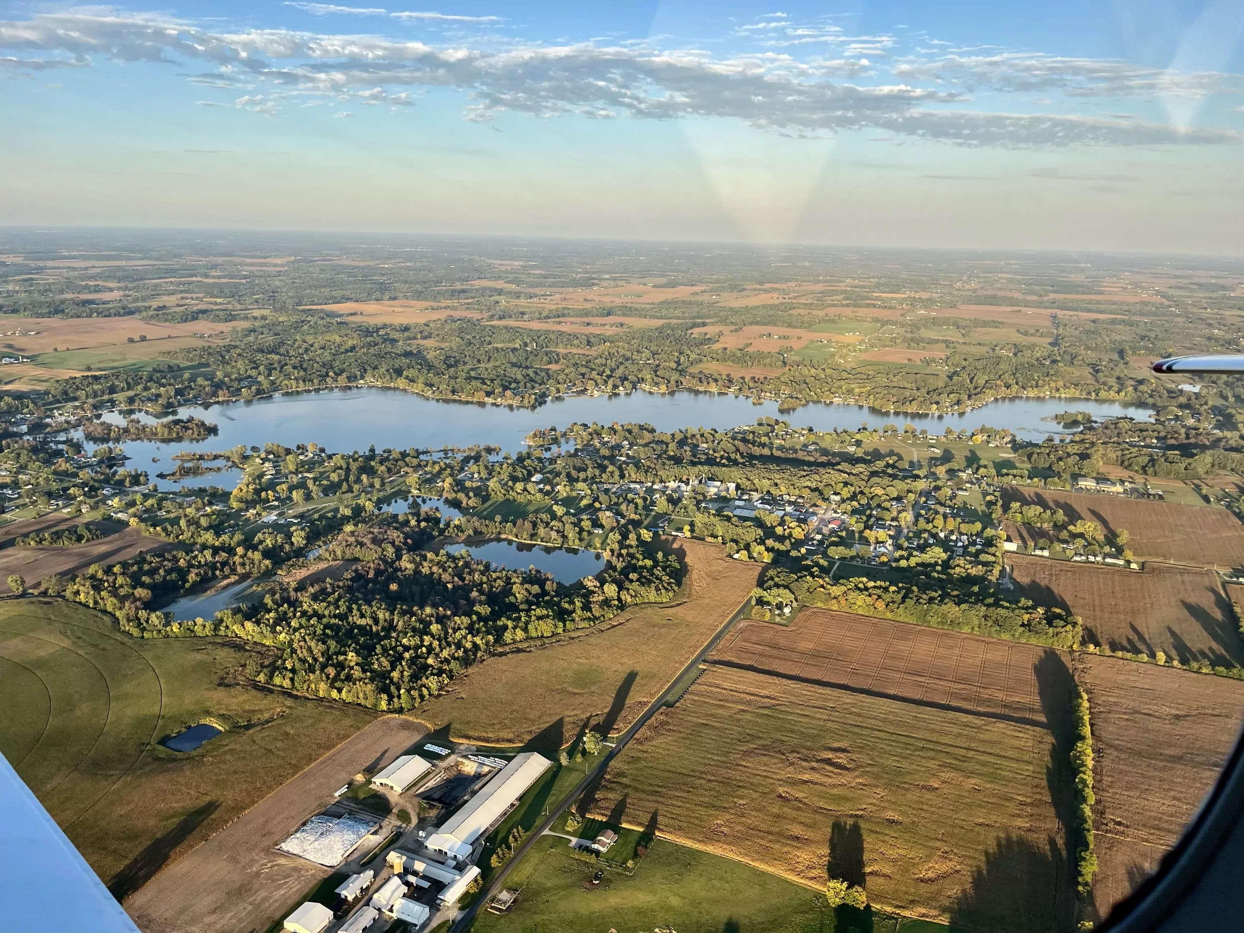 Big Turkey Lake photographed from a small plane, with tilled fields, woodlots and farm buildings covering the ground that drains toward it.